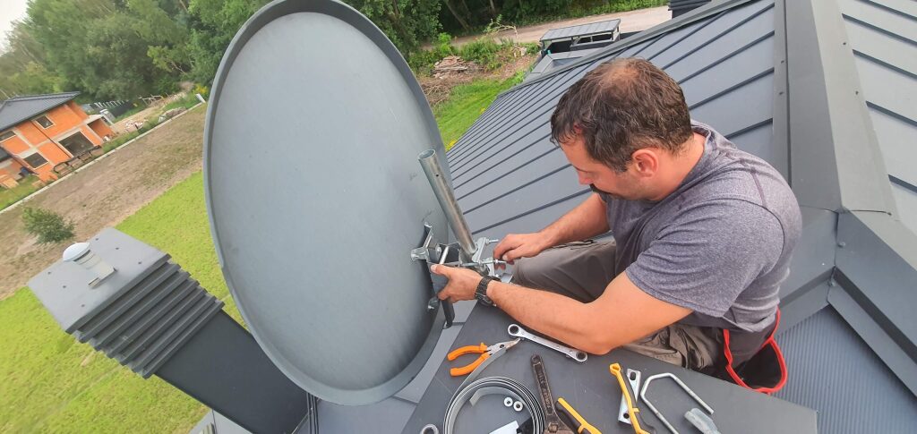 Instalator anten pracujący na dachu podczas montażu