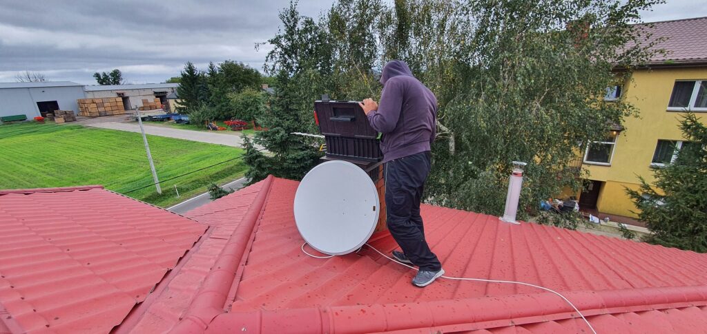Instalator anten pracujący na dachu podczas montażu
