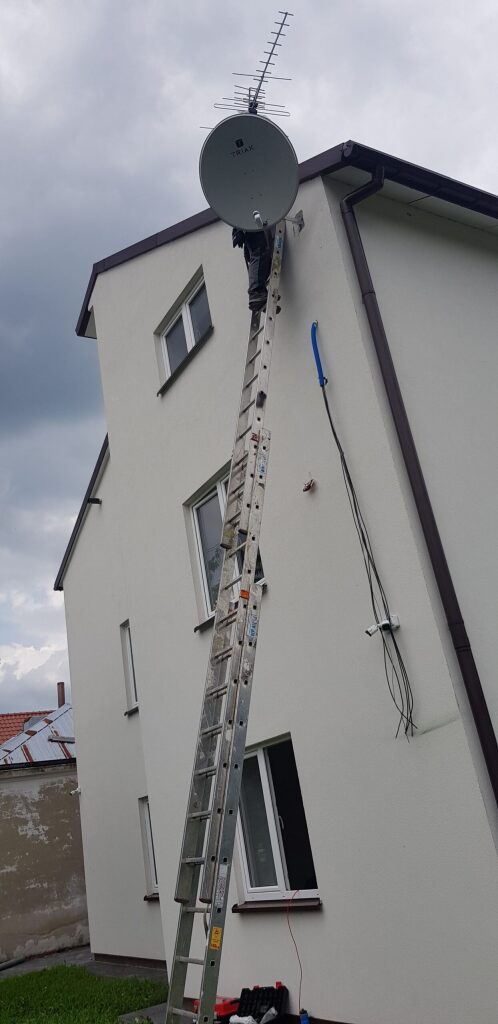 Montaż anteny satelitarnej z wysokiej drabiny przez instalatora